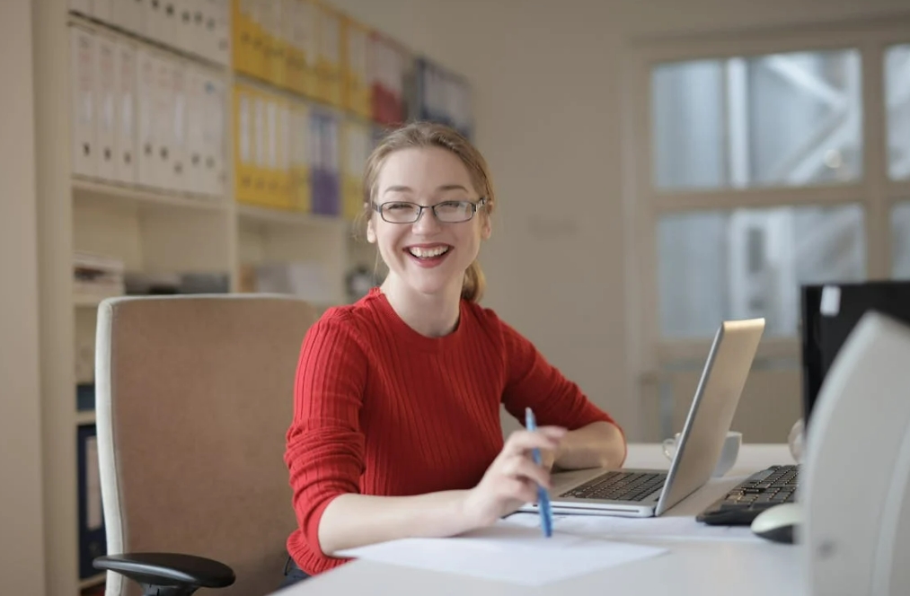 Smiling professional working on a content strategy for SaaS, planning digital marketing and content creation at a desk with a laptop and documents.