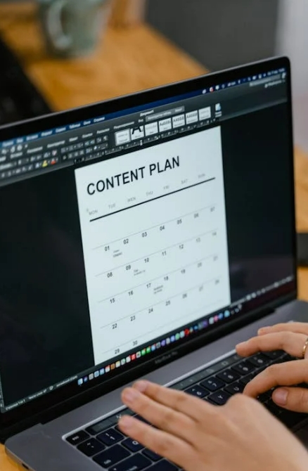 Person working on a SaaS Content Marketing plan on a laptop, displaying a content calendar in a document editor.