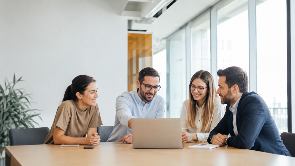 Four colleagues reviewing a B2B SaaS content marketing strategy around a laptop in a bright office