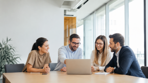Four colleagues reviewing a B2B SaaS content marketing strategy around a laptop in a bright office